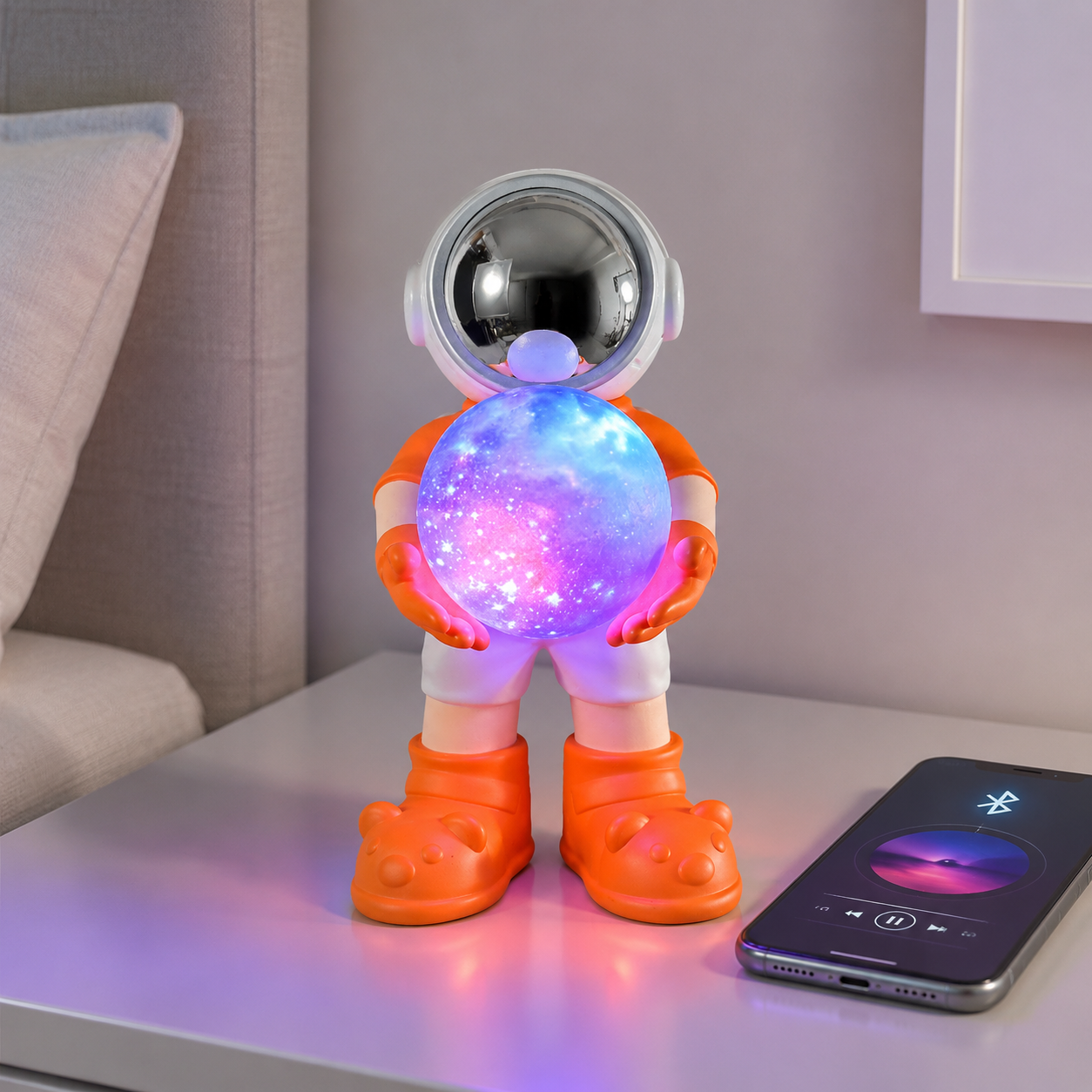 Oranje astronaut Bluetooth speaker en kleurrijke nachtlamp naast een smartphone