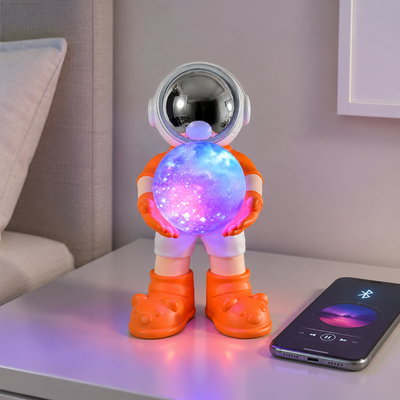 Oranje astronaut Bluetooth speaker en kleurrijke nachtlamp naast een smartphone