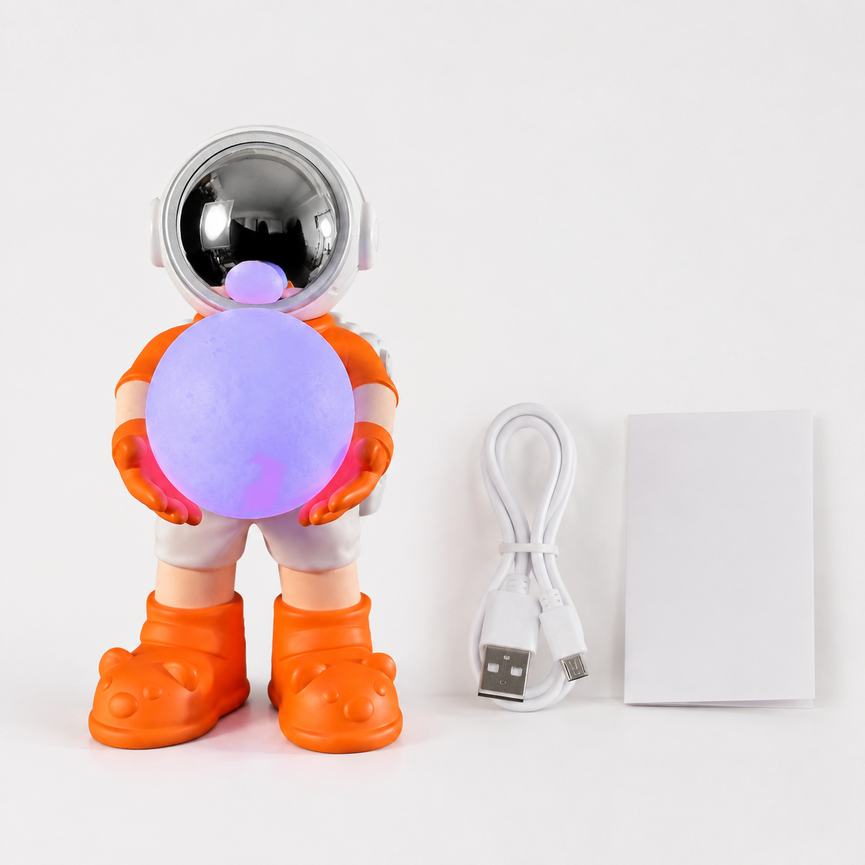 Inhoud met oranje astronaut speaker, USB-oplaadkabel en handleiding